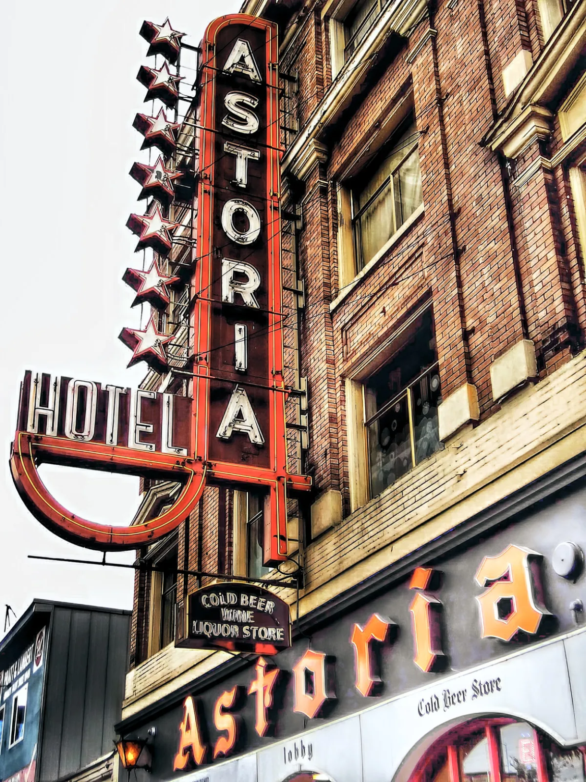 The historic Astoria Hotel in Vancouver's Downtown Eastside, featuring its iconic neon sign and brick facade, a symbol of the area's complicated history.