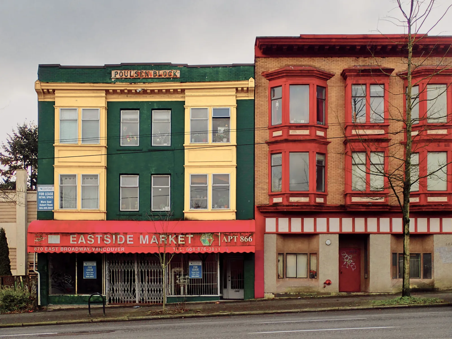 Poulsen Block with green and yellow facade and adjacent red building, Eastside Market on East Broadway in Vancouver.