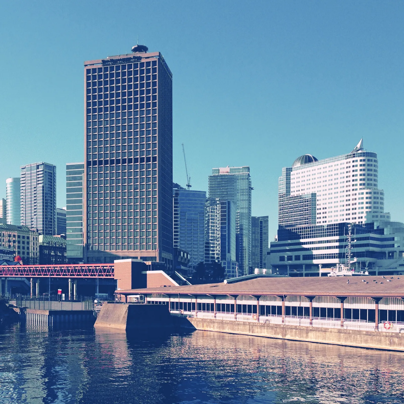 Granville Square in Vancouver, former home of the Vancouver Sun newspaper, with surrounding high-rise buildings reflecting in the waters of Burrard Inlet.