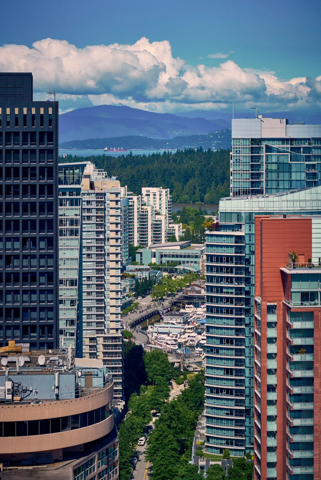 Vancouver skyscrapers with view of Coal Harbour and Lost Lagoon in Stanley Park, set against the backdrop of the North Shore Mountains.